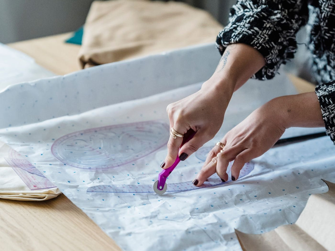 Des mains découpent un gabarit sur un plan de travail d'atelier